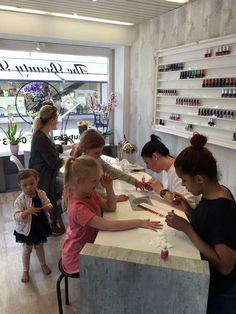 a group of people standing at a counter in a store with manicures on it