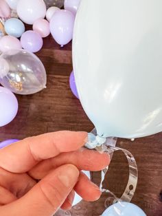 a person holding a balloon in their hand near some balloons on the table with them