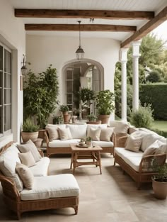 an outdoor living room with wicker furniture and potted plants on the porch area