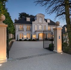 a large white house with an iron gate in front of it at night time and lit up windows