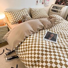 a bed with brown and white checkered comforter, pillows and pictures on the wall