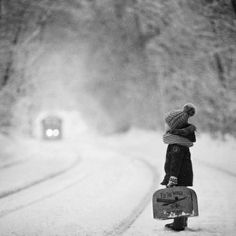 a small child is standing in the snow holding a suitcase