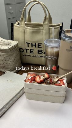 a lunch box with strawberries in it sitting on a table next to a coffee cup