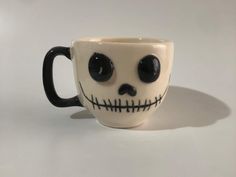 a coffee cup with black eyes and a skull face painted on the inside is sitting on a white surface