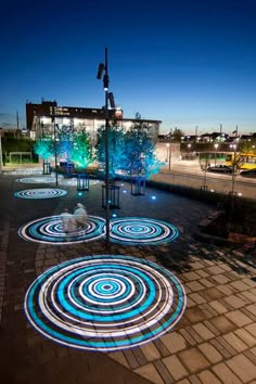 several circular lights are projected on the ground in front of a building at night time