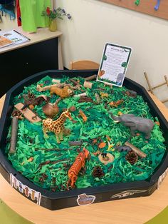 an animal themed cake with green frosting on a wooden table in a classroom setting