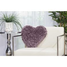 a heart shaped pillow sitting on top of a white couch next to a potted plant