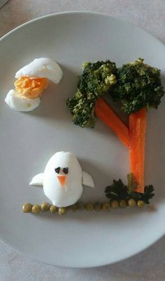 a white plate topped with broccoli, carrots and an egg in the shape of a penguin