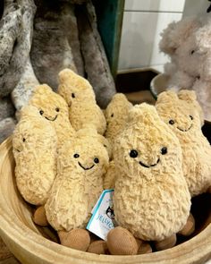 four stuffed animals sitting in a wooden bowl on top of a table next to other stuffed animals