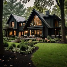 a large black house surrounded by trees and grass