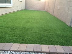 a small backyard with grass and brick pavers