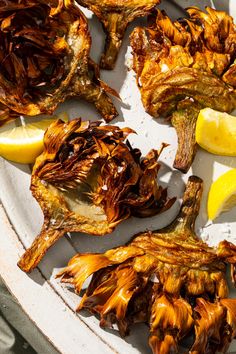 grilled artichokes with lemon wedges on a plate