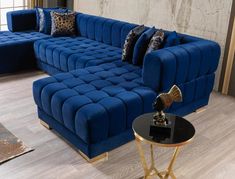 a large blue couch sitting on top of a wooden floor next to a glass table