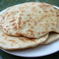 three flat breads are stacked on a white plate