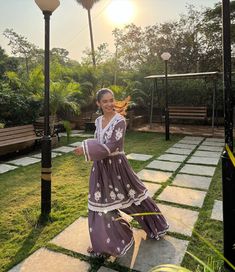 a woman in a purple dress is dancing outside