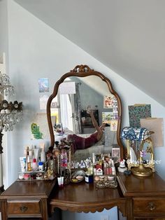 a desk with a mirror and other items on it in front of a chandelier