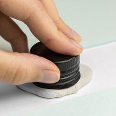 a person is pressing the button on a white and black object with their thumbnails