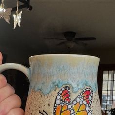 a hand holding a coffee mug with butterflies on it