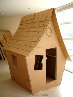 a cardboard house made to look like it is in the shape of a house with windows