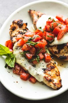 grilled chicken with tomatoes and basil on a white plate