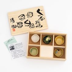 a wooden box with six small cups in it