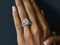 a woman's hand with two wedding rings on her left and the other hand holding an engagement ring