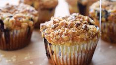 several muffins with crumbs on them sitting on a wooden table top