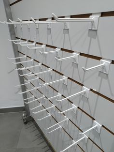 a wall mounted rack with multiple white clothes hangers on it's sides and two rows of hooks attached to the wall