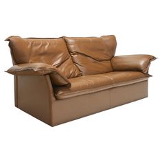 a brown leather couch with two pillows on it's back and armrests