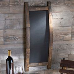 a bottle of wine sitting on top of a wooden table next to a chalkboard