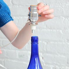 a woman is holding a wine bottle with a corkscrew attached to the top