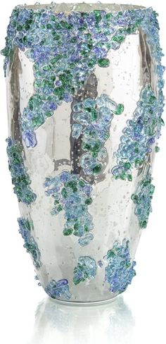 a glass vase with blue and green flowers on it's sides, in front of a white background