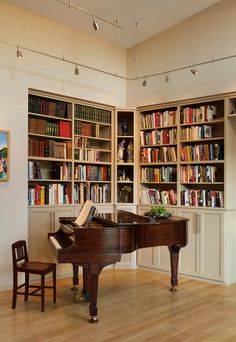 a grand piano sits in front of a bookshelf