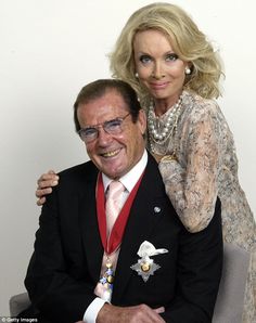 a man and woman are sitting on a chair posing for the camera with their arms around each other