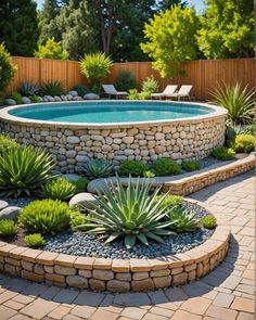 an outdoor pool surrounded by rocks and succulents in the middle of a garden