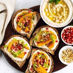 breads with different toppings are arranged on a plate next to bowls of food