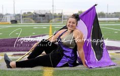 a woman sitting on the ground with a purple and black kite next to her legs