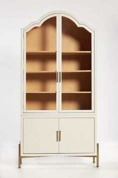 a white bookcase with glass doors and gold handles