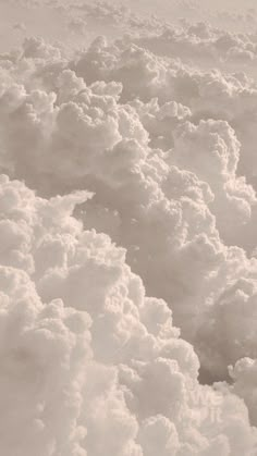 black and white photograph of clouds in the sky from an airplane window, looking down