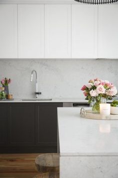 a white kitchen counter with flowers and candles on the counter top in front of it