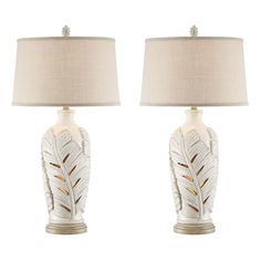 a pair of white ceramic lamps with gold accents on each lamp and a beige linen shade