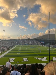 a football stadium filled with lots of people watching the game on a cloudy day at sunset