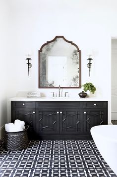 a black and white bathroom with a large mirror above the sink, rug on the floor