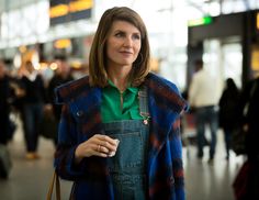 a woman standing in an airport holding a cup