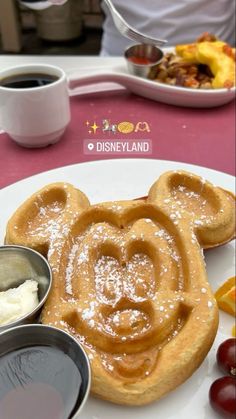 mickey mouse waffles on a white plate with fruit and coffee in the background