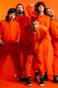 a group of people in orange jumpsuits posing for a photo with their hands on their head