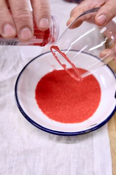 someone is pouring red liquid into a white bowl