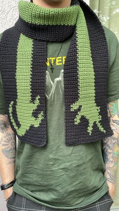 a man wearing a green and black crocheted scarf with an alligator on it