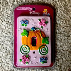 a pink switch plate with flowers and a pumpkin on the front, sitting on a carpeted surface