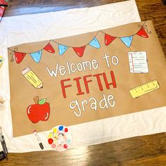 a welcome sign is displayed on a table with other school supplies around it and the words, welcome to fifth grade